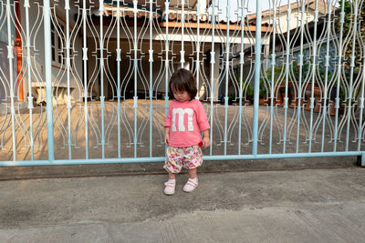 Girl standing against metallic gate 