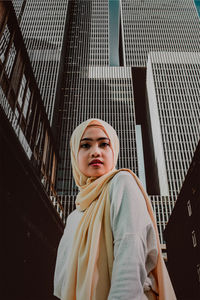 Portrait of beautiful young woman standing against wall