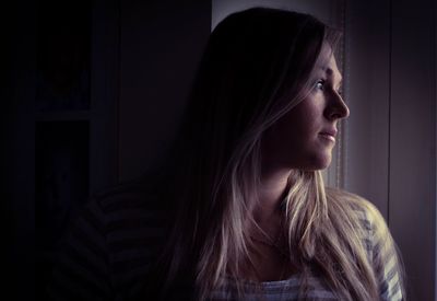 Thoughtful young woman looking away while leaning at home
