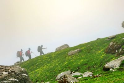 Low angle view of people walking on mountain against clear sky