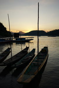 Boat moored on river against sky during sunset