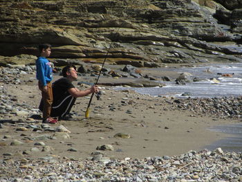 Side view of men on rock at beach