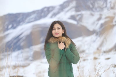 Portrait of young woman standing on snow covered landscape