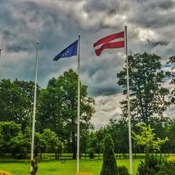 Trees on landscape against cloudy sky