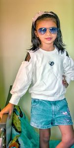 Portrait of smiling girl standing against wall