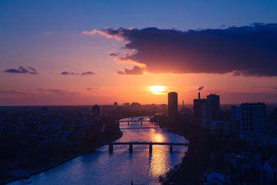 River amidst buildings against sky during sunset