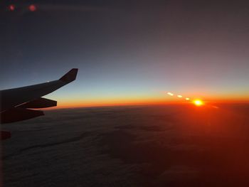 Close-up of airplane wing against sky during sunset