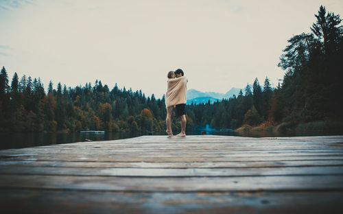 Rear view of man standing by trees against sky