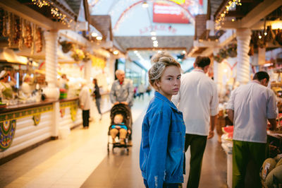 Portrait of young woman standing in illuminated market