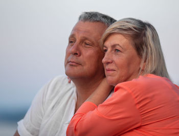 Thoughtful mature couple looking away against sky