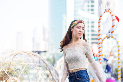 Young woman looking away while standing outdoors