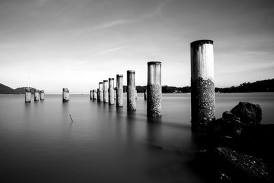 Wooden posts in sea against sky