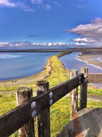 Wooden posts on beach against sky