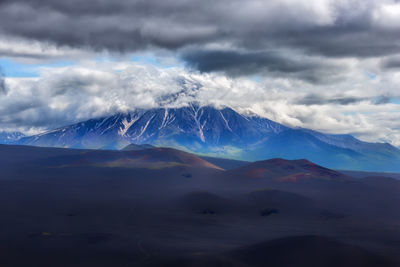 Scenic view of snowcapped mountains against cloudy sky