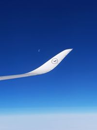 Low angle view of airplane flying against clear blue sky