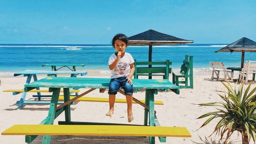 Front view of children sitting on beach chair against seashore