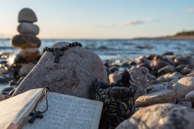 Close-up of stones on rock at beach against sky