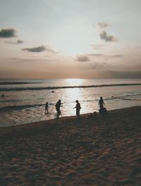Silhouette people on beach against sky during sunset
