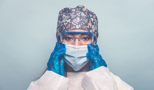 Portrait of doctor wearing mask against colored background