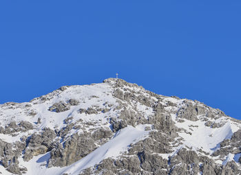 Low angle view of snowcapped mountain against clear blue sky