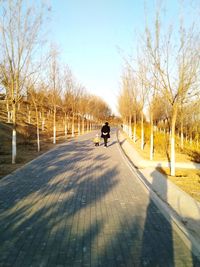 Rear view of grandmother and granddaughter walking on footpath