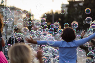 Cheerful kids playing amidst bubbles on road