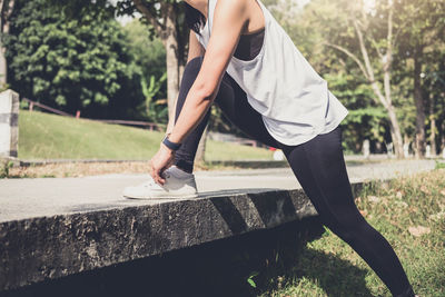 Low section of woman tying shoelace in park