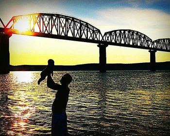 Silhouette of people in river at sunset