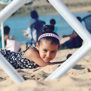 Portrait of girl lying on sand at beach