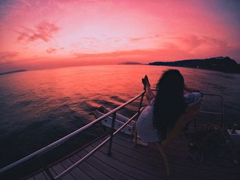 Woman relaxing by sea at sunset