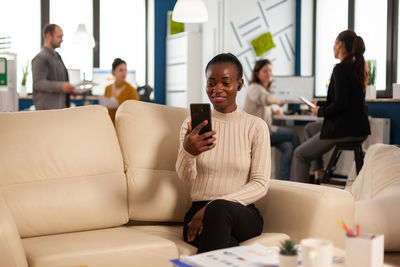 Businesswoman using phone with colleagues in background