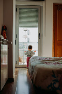 Rear view of baby boy standing by door at home