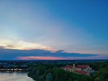 Scenic view of river by buildings against sky during sunset