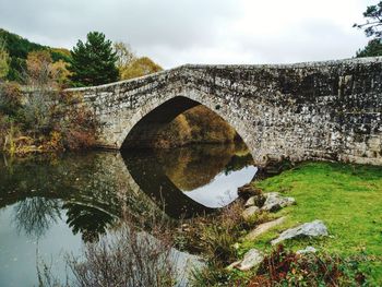 Arch bridge over river against sky