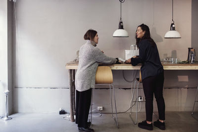 Full length of smiling colleagues standing by table at workshop