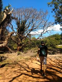 Rear view of woman walking on street amidst trees