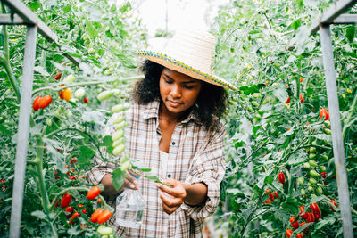 Portrait of smiling young woman standing by plants