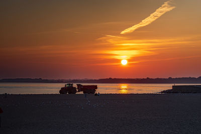 Silhouette people on beach against sky during sunset