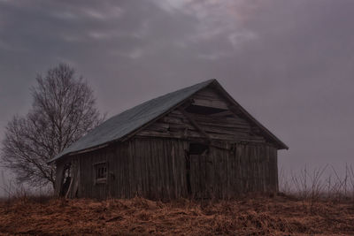 Barn on grassy field against cloudy sky