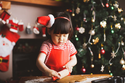 Girl making cookies at table during christmas