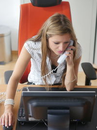 Young woman using phone while sitting at home