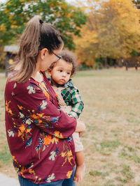 Mother out on a lovely fall or autumn day embracing her son