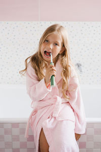 Cute girl brushes her teeth in the bathroom hygiene concept