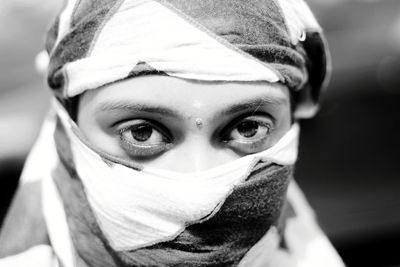 Close-up portrait of young woman with scarf wrapped on face