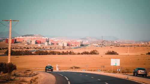 Vehicles on road against clear sky