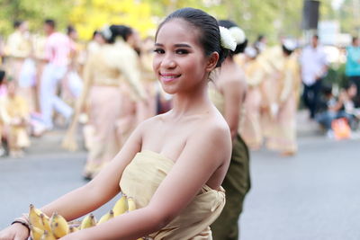 Portrait of smiling woman with arms raised outdoors