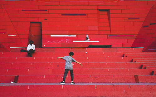Rear view of boy walking against red wall