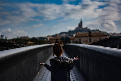 Rear view of woman with umbrella against sky in city