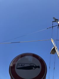 Low angle view of road sign against clear blue sky