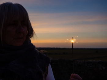 Portrait of woman holding sun over land against sky during sunset